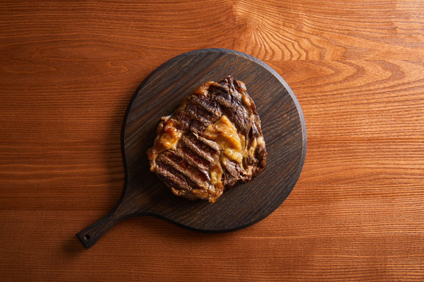 top view of tasty grilled steak served on wooden board - Fotó, kép