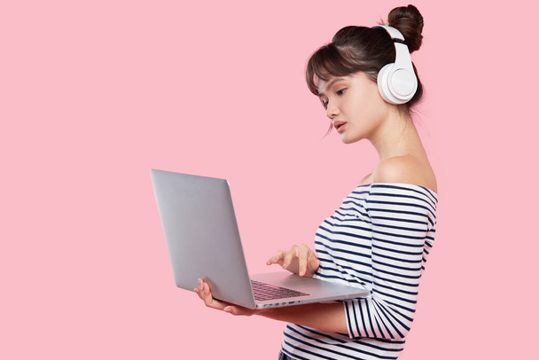 5G Unlimited Internet Advertising. distance learning online. Portrait of young asian woman using laptop and listening to music on wireless headphones.  - Фото, изображение