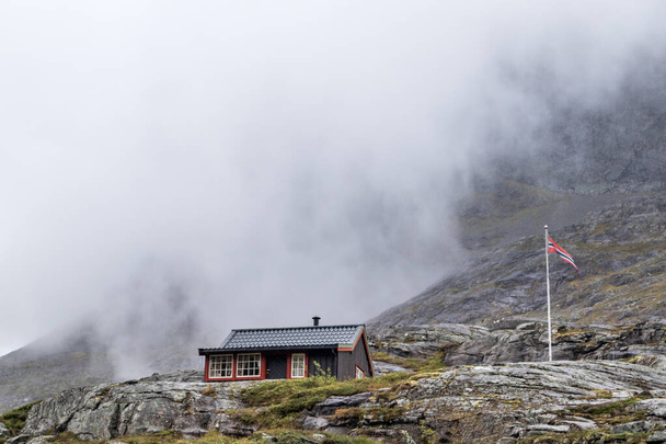 Traditionelle norwegische Berghütten aus Holz am Trollstigen, Norwegen. Bewölkter weißer Himmel und felsige Hügel. - Foto, Bild