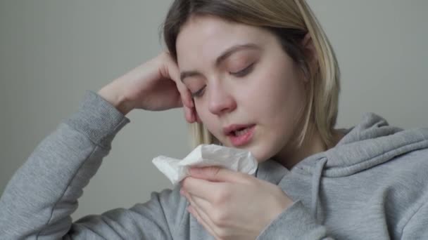 A girl with tired eyes is sick and sneezes but laughs and does not lose heart. Symptom of Orvi, coronovirus, flu, acute respiratory disease, allergy. - Metraje, vídeo