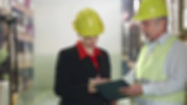An blurry view online sales warehouse  worker is providing a stock report to the warehouse manager.  suitable for use as an e commerce business background. - Photo, Image