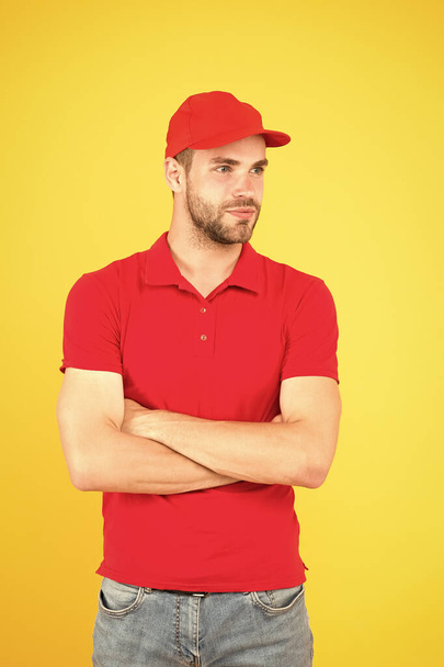 friendly shop assistant. food order deliveryman. cashier vacancy. Fast and free parcel delivery. dealer yellow wall. Salesman cashier career. man delivery service in red tshirt and cap - Foto, Imagem