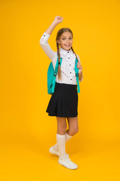 Come with me. smart looking student on yellow background. modern education concept. back to school. happy little girl in uniform carry backpack. child after lessons. school fashion style - Photo, Image