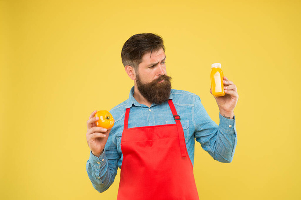 Vegetarian nutrition. Smoothie drink. Delivering fresh vitamins. Hipster smoothie beverage. Fresh juice. Squeezing smoothie. Man bearded chef hold organic natural tomato and bottle yellow background - 写真・画像