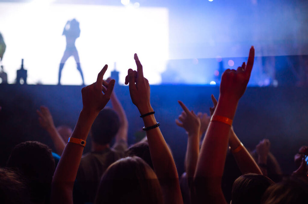 Tłum z podniesionymi rękami na festiwalu muzycznym. Fani cieszą się koncertem rockowym z lekkim show i klaskającymi dłońmi. - Zdjęcie, obraz