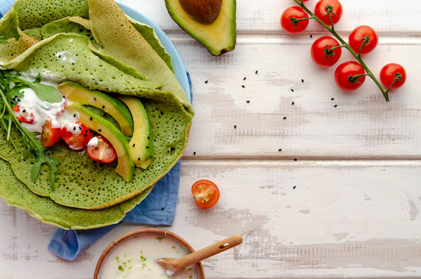 Spinat- oder Matcha-Pfannkuchen mit Rucolablättern und Avocadoscheiben - Foto, Bild