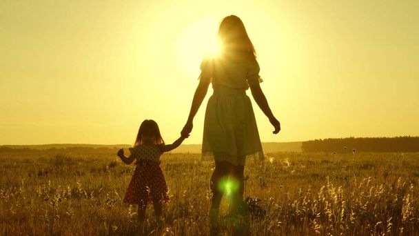 free Happy family with a child walks in countryside. healthy Mother and baby are resting in park. happy childhood. little daughter and mother walk across field holding hands. baby holds moms hand. - Foto, Bild