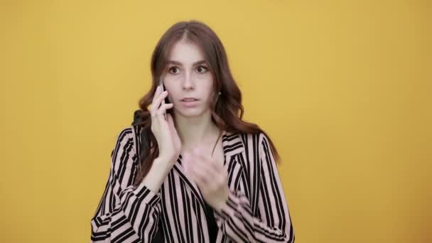Chica impactada hablando por teléfono, boca cubierta con su mano. Concepto de malas noticias
 - Metraje, vídeo