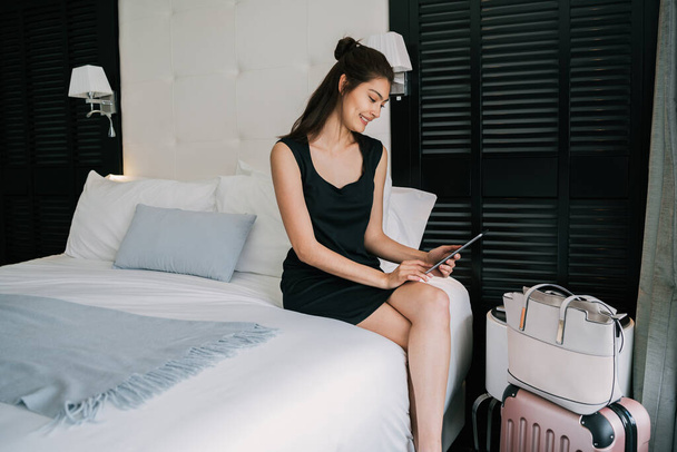 Portrait of young businesswoman using her mobile phone at the hotel room. Business travel concept. - Foto, immagini