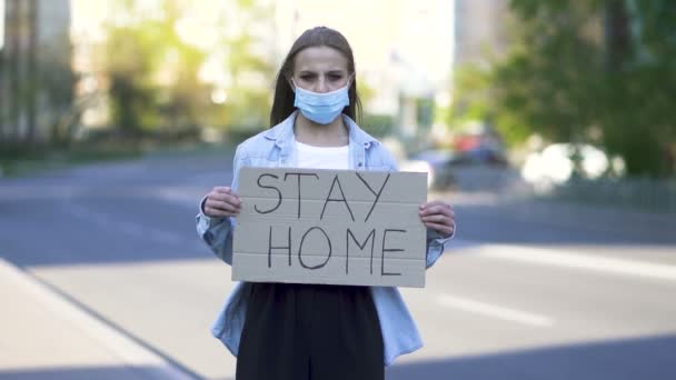 スローモーション。街中のポスターで医療マスク抗議の若い女性。単語パンデミックチーム - 映像、動画