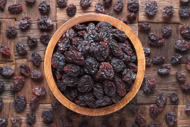 dried grapes, dark raisins in bowl on wooden table background. - Photo, Image