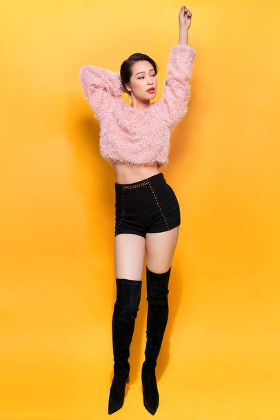 Stunning cute girl posing with pleasure on yellow background. Indoor photo of dancing young lady in trendy fur coat to camera. - Fotó, kép