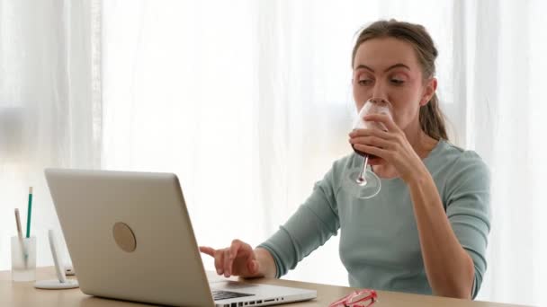 Woman working on a laptop with a glass of wine - Filmagem, Vídeo