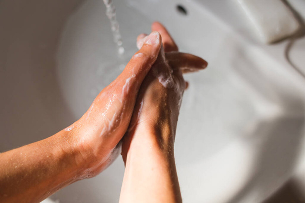 Eine Frau wäscht ihre Hände mit Seife, Hygiene, Hygieneverfahren, Schaum auf weiblichen Händen aus nächster Nähe, Schutz vor Viren und Bakterien. - Foto, Bild