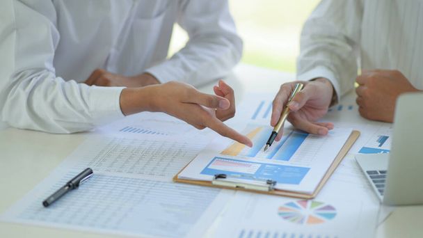Business office staff are analyzing data graphs to summarize annual results. - 写真・画像