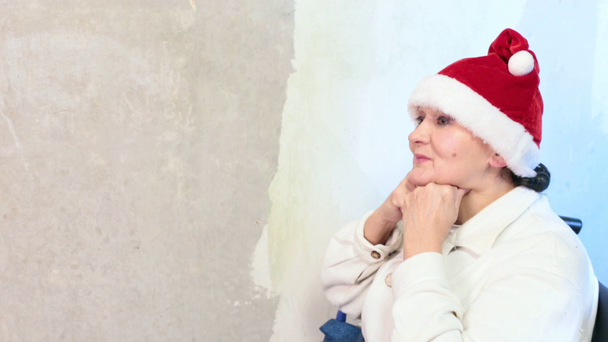 Vanhempi nainen, jolla on jouluhattu pyörätuolissa
 - Materiaali, video