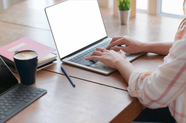 Close-up widok firmy kobieta ręka jest za pomocą laptopa na stole z kawą w wygodnym biurze. - Zdjęcie, obraz