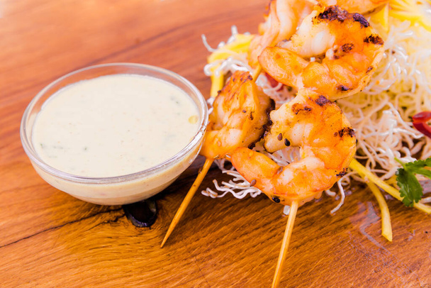 Shrimp skewers in coconut curry and Asian sauce on a wooden board. Horizontal photo - Fotografie, Obrázek