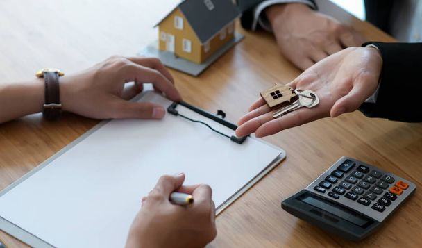 Signing a house purchase contract between the buyer and the seller and delivering the house key. - Foto, Imagen