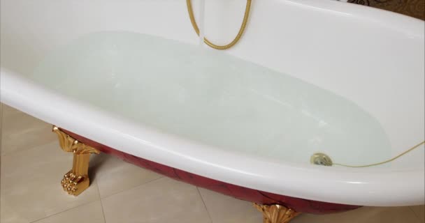 Beyaz lavaboya akan musluk. Musluktan gelen bir su akıntısı küveti doldurur. Küveti doldur. Küveti suyla doldur. Musluktan banyoya kadar su. Kara büyü 4k - Video, Çekim