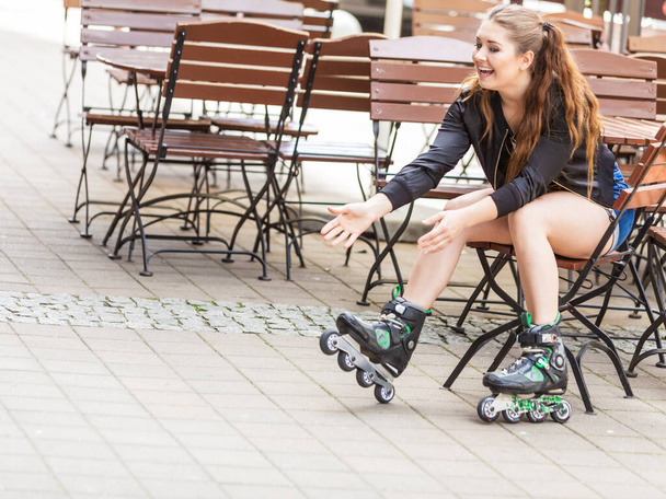 Happy joyful young woman wearing roller skates sitting in town. Female being sporty having fun during summer time. - Foto, Imagem