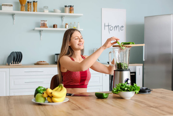 Sporty woman making smoothie in kitchen at home - Photo, Image