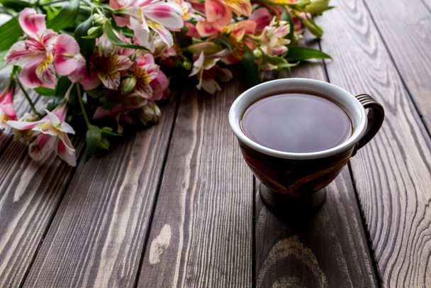 taza de té y Alstroemeria en el fondo de madera. flores sobre un fondo marrón. copiar texto. hermoso ramo
. - Foto, Imagen