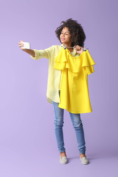 African-American teenage fashion blogger with mobile phone on color background - Foto, afbeelding