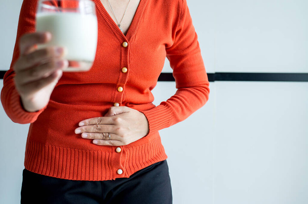 Woman having a stomach ache and hands holding a glass of milk,Allergy dairy intolerant,Lactose intolerance concept - Foto, Imagen