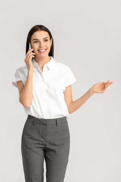 Beautiful young secretary talking by phone on white background - Foto, afbeelding