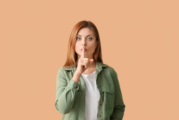 Young woman showing silence gesture on color background - Photo, Image