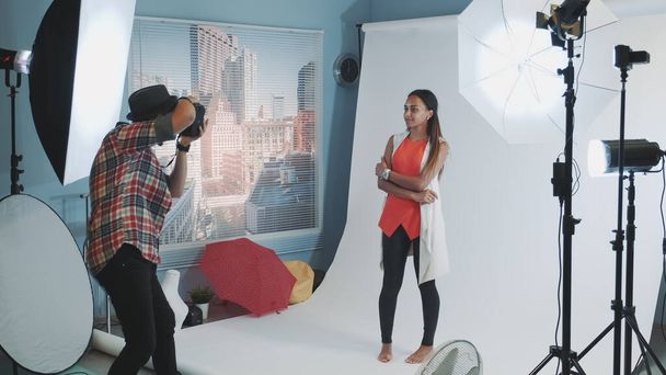 Fotógrafo profesional pidiendo a modelo que cambie de postura mientras hace una sesión de fotos en el estudio
 - Foto, Imagen
