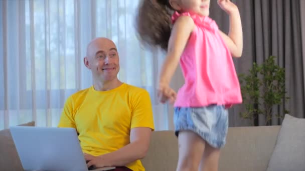 Fiatal férfi szabadúszó dolgozik egy laptop ül egy kanapén otthon, üzletember gépel egy laptop, fókuszált ember használja a számítógépet, hogy tanulmányozza az online munka otthon, amikor egy gyerek fut hozzá a fia. - Felvétel, videó