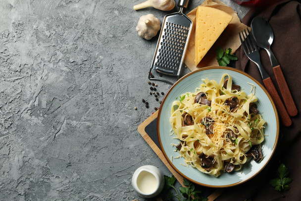 Samenstelling met bord smakelijke pasta en ingrediënten voor het koken op grijze achtergrond - Foto, afbeelding
