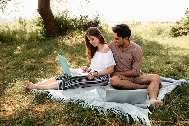 A beautiful teen couple man and women working use laptop to working at outdoor park holiday - Photo, image