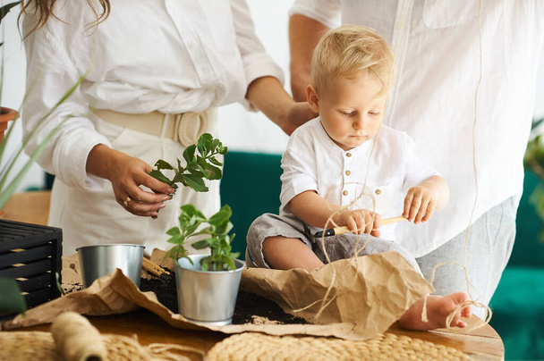 Happy family working at home. Transplanting plants with their child - Foto, imagen