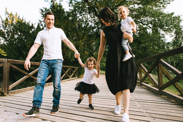 Handsome young father and beautiful mother in sunny summer nature playing with their cute small childrens - Foto, imagen