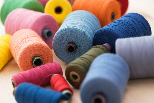 Пошив одежды. Много разноцветных нитей на столе - Фото, изображение