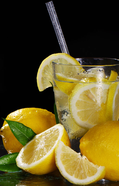 Cocktail with fresh wet lemons on black background - Photo, Image