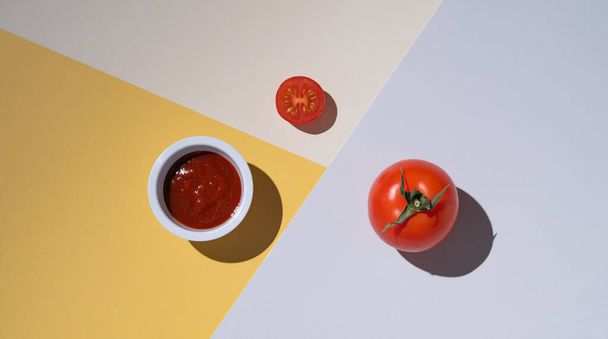 Свежий сочный помидор и кетчуп на разноцветном фоне с твёрдой тенью. концепт фото. Горизонтальная ориентация. Вид сверху и пространство для копирования
 - Фото, изображение