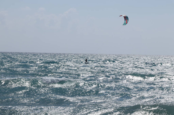 Kiteboarding είναι ένα άθλημα δράσης που συνδυάζει πτυχές της wakeboarding, snowboarding, windsurfing, surfing, αλεξίπτωτο πλαγιάς, skateboarding και ιστιοπλοΐα σε ένα ακραίο άθλημα. Kiteboarder στη Μεσόγειο θάλασσα. - Φωτογραφία, εικόνα