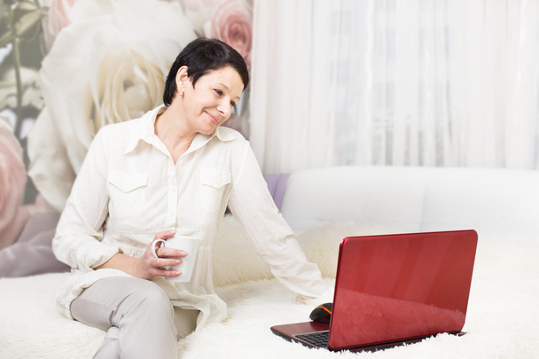 Woman using laptop while sitting on bed at home - Zdjęcie, obraz