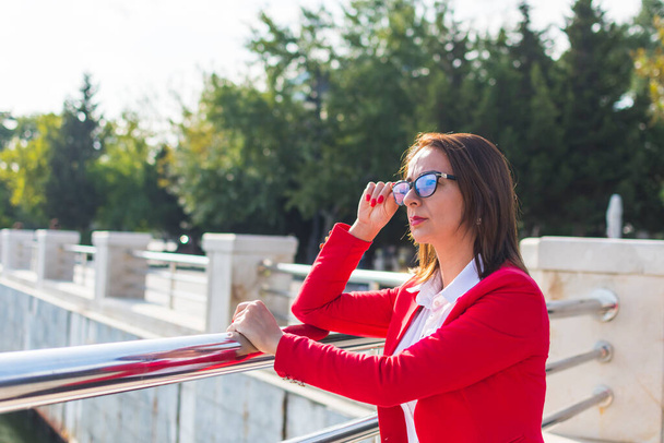 ділова жінка в окулярах на відкритому повітрі дивиться вдалину
 - Фото, зображення