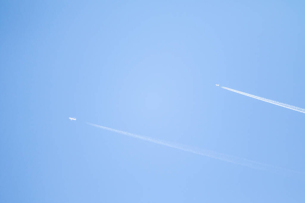 Fehér nyom egy kék égbolton lévő repülőgépről. A szárnyas utasszállító repülőgép nyomvonala a tiszta kék égbolton - Fotó, kép