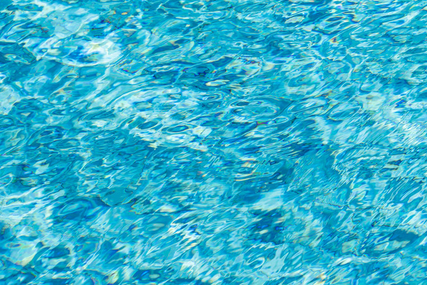 Tło powierzchni wody. Błękitna woda z odbiciami słońca. Grudki wody w basenie. - Zdjęcie, obraz