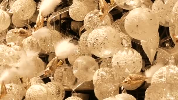 Wiedeń, Austria - 21 grudnia 2019: Białe szkło Zabawki świąteczne i ozdobne kulki na stoisku jarmarku bożonarodzeniowym. Nocny strzał Wiedeń Bożonarodzeniowy rynek - Materiał filmowy, wideo