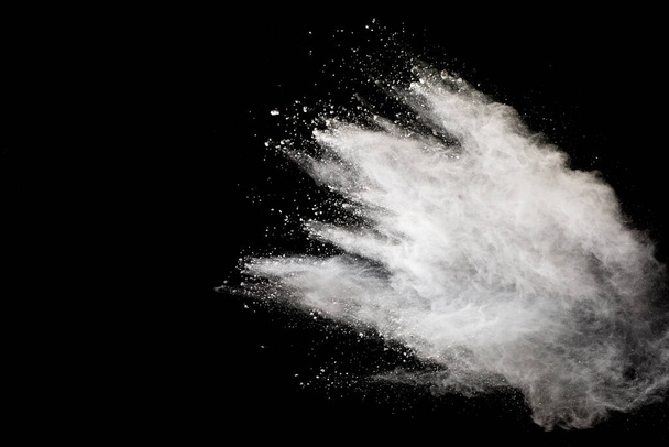 Άσπρη έκρηξη σκόνης που απομονώνεται σε μαύρο φόντο.Λευκά σωματίδια σκόνης πιτσιλίζουν. - Φωτογραφία, εικόνα