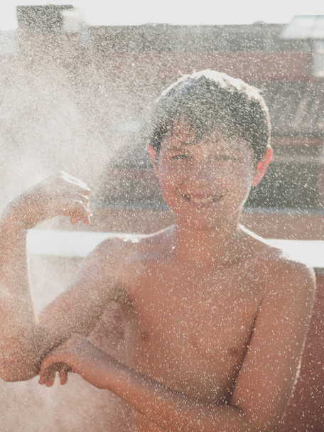Iloinen nuori teini nauttia suihkussa letku ulkona terassilla
 - Valokuva, kuva