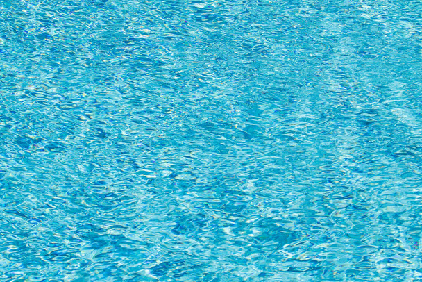 Tło powierzchni wody. Błękitna woda z odbiciami słońca. Grudki wody w basenie. - Zdjęcie, obraz