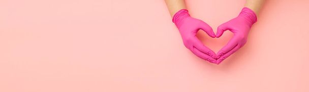 Thanks you doctors - horizontal banner with copy space for text. Female hands in red gloves show symbol of heart on pink background. - Photo, image
